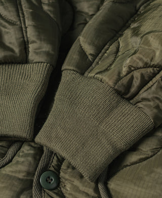Olive quilted jacket sleeve cuff with ribbed knit and snap button