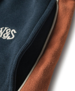 Close-up of navy seam and rust side stripe on sweatpants