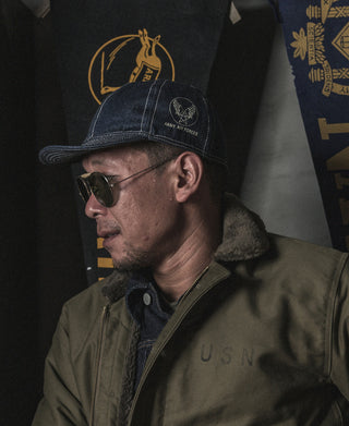 Indigo denim A-3 style cap on a man’s head, side profile with emblem patch