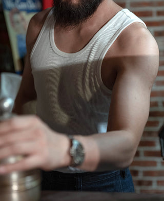 Close view of white ribbed tank top on model, sleeveless armhole and neckline