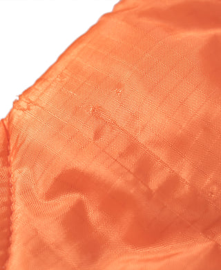 Orange ripstop vest fabric close-up with quilted pattern and textured weave