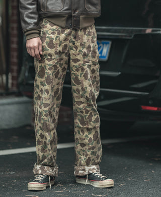 Reversible duck hunter camo pants worn, close view of front with button fly and belt loops