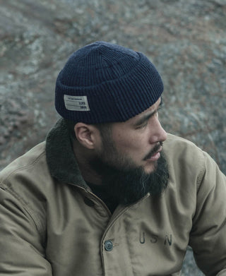 Navy knit watch cap beanie with folded cuff and small white label on front