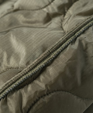 Olive quilted jacket liner fabric close-up with thick edge piping and stitching