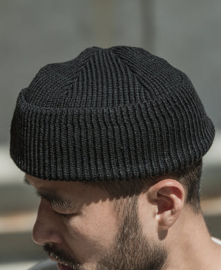 Black rib-knit watch cap on wearer, side profile
