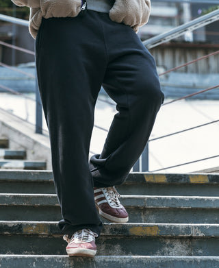 Black terry sweatpants on stairs, straight fit with side pockets and elastic cuff