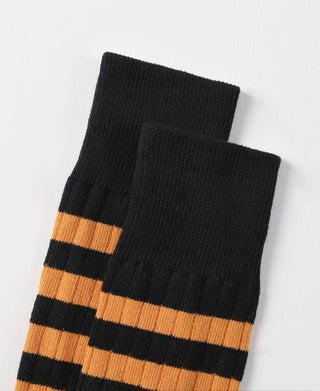 Folded pair of black crew socks with orange horizontal stripes.