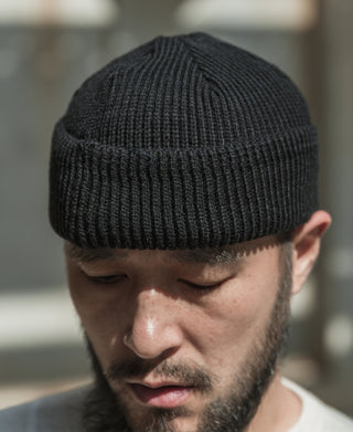 Black rib-knit watch cap on wearer’s head, close-up view