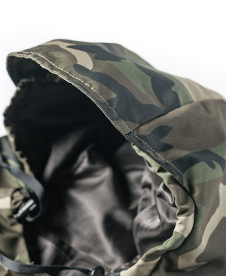 Woodland camo parka hood edge close-up with black lining and stitched seam.