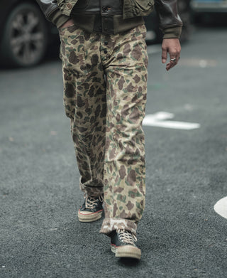 Reversible camo pants worn, leg view with cuffs and layered pattern in green tan tones