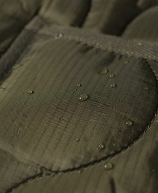 Quilted olive ripstop nylon jacket fabric with water-beading on pocket panel