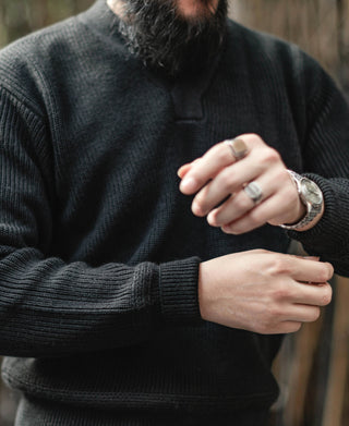 Black V-neck sweater close-up showing ribbed knit collar and sleeve cuff