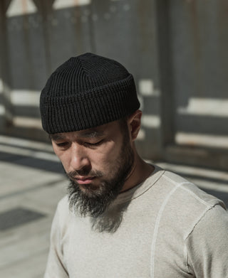 Man wearing black ribbed knit watch cap beanie with folded cuff
