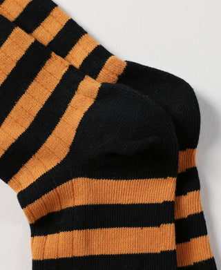 Striped black and orange cotton socks with ribbed knit texture, close-up side view