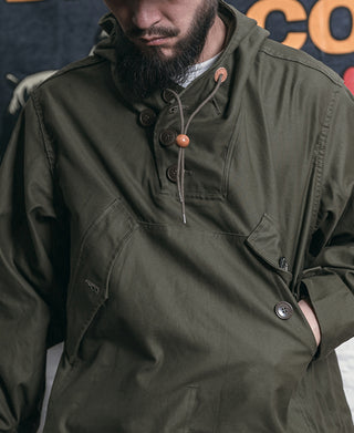 Olive field parka close-up with hood drawcord, snap placket, and chest patch pocket