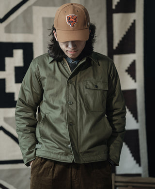 Olive deck jacket worn with a button front and flap chest pocket