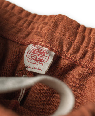 Orange sweatpants with embroidered brand patch at waistband and ribbed cuffs