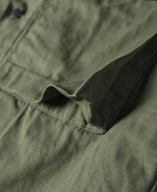 HBT jacket sleeve cuff with stitched seam and snap-tab opening, olive green.