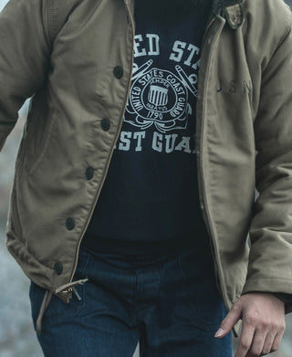 Navy sweatshirt with Coast Guard front logo under a light gray zip jacket