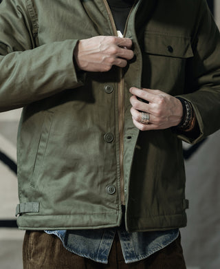Olive deck jacket front close-up with metal zipper and button placket