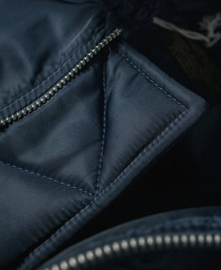 Navy flight jacket close-up of zipper hardware and stitched pocket panel