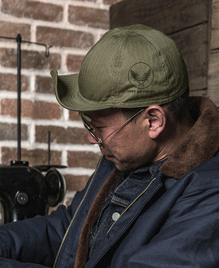 Olive flight cap with curved brim and front embroidered emblem, angled view