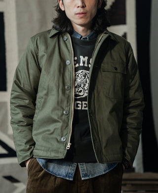 Olive deck jacket worn over a hoodie, featuring chest flap pockets and buttons