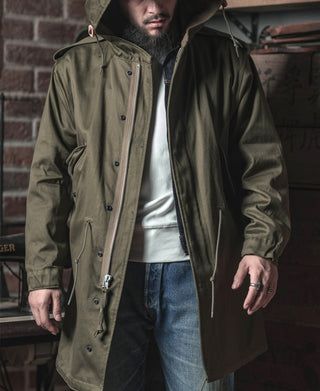 Olive M-1951-style parka with hood, front zipper and snap buttons, flap pockets