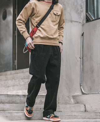 Black corduroy trousers with wide legs, side pockets, and zipper fly