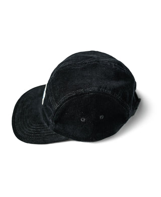 Black corduroy 5-panel cap with triangular logo patch, studio view