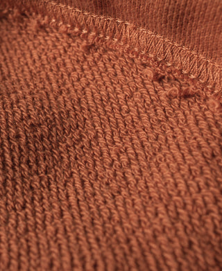 Orange terry cotton sweatpants fabric close-up showing ribbed texture and stitching