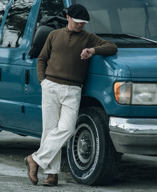 Olive wool high-neck sweater with button placket, styled with white pants