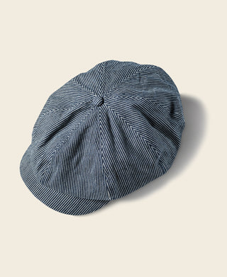 Striped denim newsboy cap in dark blue with white pinstripes and stitched crown.