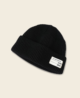 Black ribbed knit watch cap with folded cuff and small woven brand tag