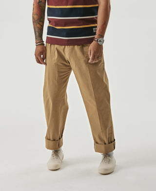 Yellow chino trousers with front pleats, cuffed hems, and side pockets
