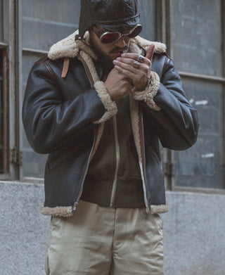 Dark brown shearling-lined flight jacket with tan collar and cuffs, front zip closure