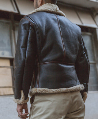 Dark brown leather flight jacket back view with tan shearling trim at hem and collar