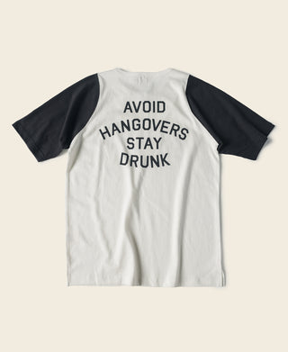 White raglan t-shirt with black sleeves, quarter-zip and 'AVOID HANGOVERS STAY DRUNK' print