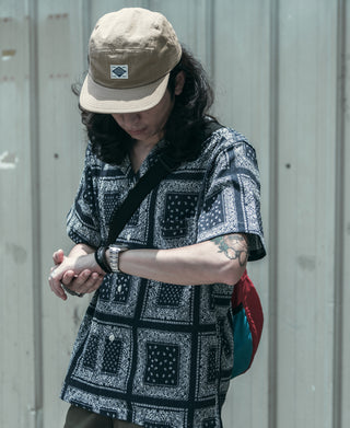 Khaki 5-panel cap on model, curved brim and front woven logo patch
