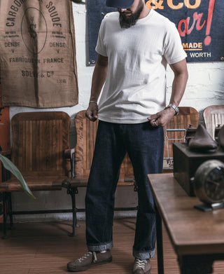 White crew-neck athletic t-shirt with short sleeves, worn with dark denim jeans