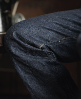 Close-up of dark indigo denim fabric and curved seam on the jeans leg