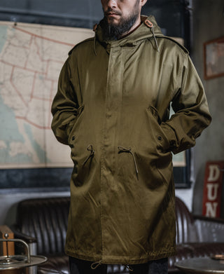Olive parka with hood and two front pockets; zipper and snap closures visible