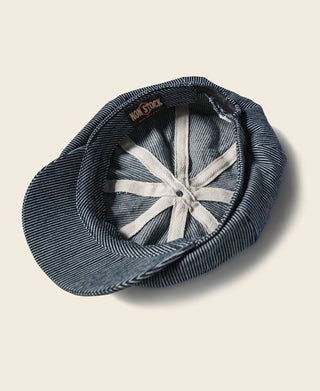 Striped denim newsboy cap interior, showing dark-blue lining and fan-stitched crown.