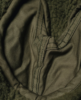 Olive jacket interior seam close-up with stitched pocket edge