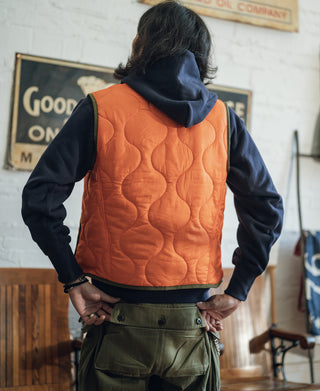 Orange quilted padded vest from behind with dark trim and raised collar
