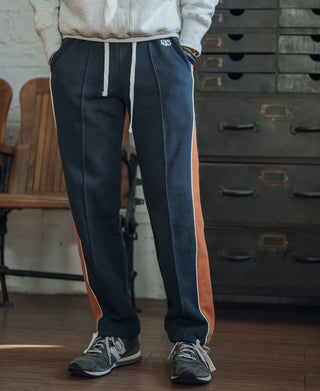 Navy straight-leg sweatpants with rust side stripe, elastic cuff, and drawstring