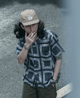 Khaki 5-panel cap with curved brim, front logo patch visible, worn on model