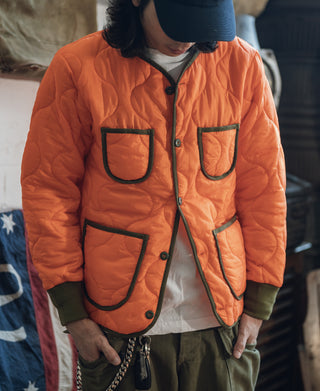 Orange padded ripstop jacket with dark trim, button front, and chest flap pockets