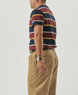 Yellow pleated chino trousers with side pockets and belt loops; cuffed hems
