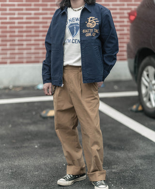 Navy tour jacket worn with tan pants and sneakers, front zip and flap pockets visible